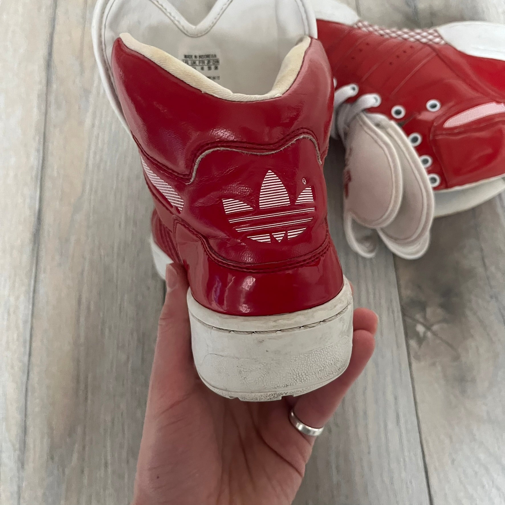 Adidas Originals Metro Attitude Logo Heart Sneakers are women’s sneakers released in 2012, featuring a red suede upper with matching University-Red accents. The design includes dual heart-shaped tongues in white with red Adidas logos, paired with a white sole and laces. Metro Attitude Logo Heart W model (G61014) inspired by Jeremy Scott collaborations.