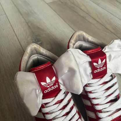 Adidas Originals Top Ten Hi Sleek Bow Sneakers are women’s high-top sneakers in University-Red and white leather. They feature a removable white bow on the tongue, white Adidas stripes, laces, and a white sole. Released under product number G61361, the sneakers include patent leather details for a polished finish.