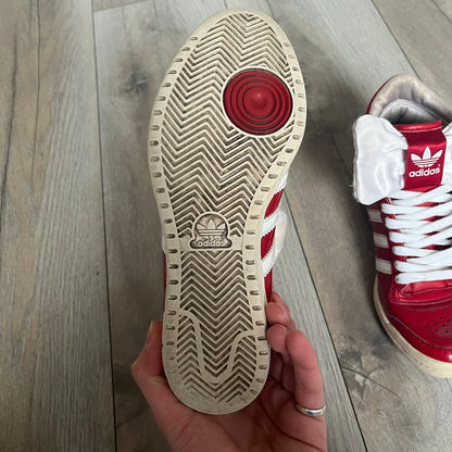 Adidas Originals Top Ten Hi Sleek Bow Sneakers are women’s high-top sneakers in University-Red and white leather. They feature a removable white bow on the tongue, white Adidas stripes, laces, and a white sole. Released under product number G61361, the sneakers include patent leather details for a polished finish.