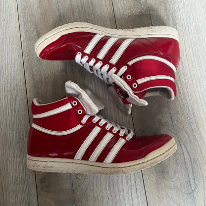 Adidas Originals Top Ten Hi Sleek Bow Sneakers are women’s high-top sneakers in University-Red and white leather. They feature a removable white bow on the tongue, white Adidas stripes, laces, and a white sole. Released under product number G61361, the sneakers include patent leather details for a polished finish.