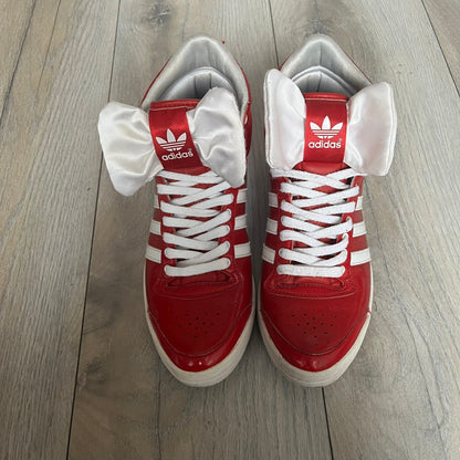 Adidas Originals Top Ten Hi Sleek Bow Sneakers are women’s high-top sneakers in University-Red and white leather. They feature a removable white bow on the tongue, white Adidas stripes, laces, and a white sole. Released under product number G61361, the sneakers include patent leather details for a polished finish.