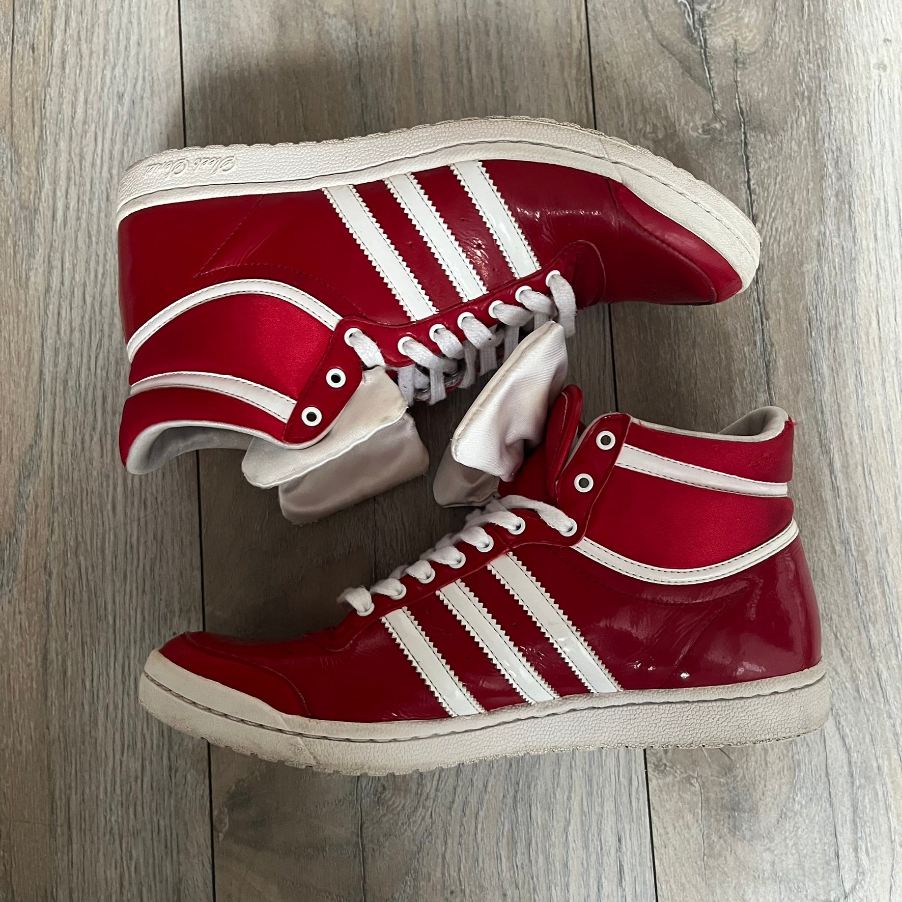 Adidas Originals Top Ten Hi Sleek Bow Sneakers are women’s high-top sneakers in University-Red and white leather. They feature a removable white bow on the tongue, white Adidas stripes, laces, and a white sole. Released under product number G61361, the sneakers include patent leather details for a polished finish.
