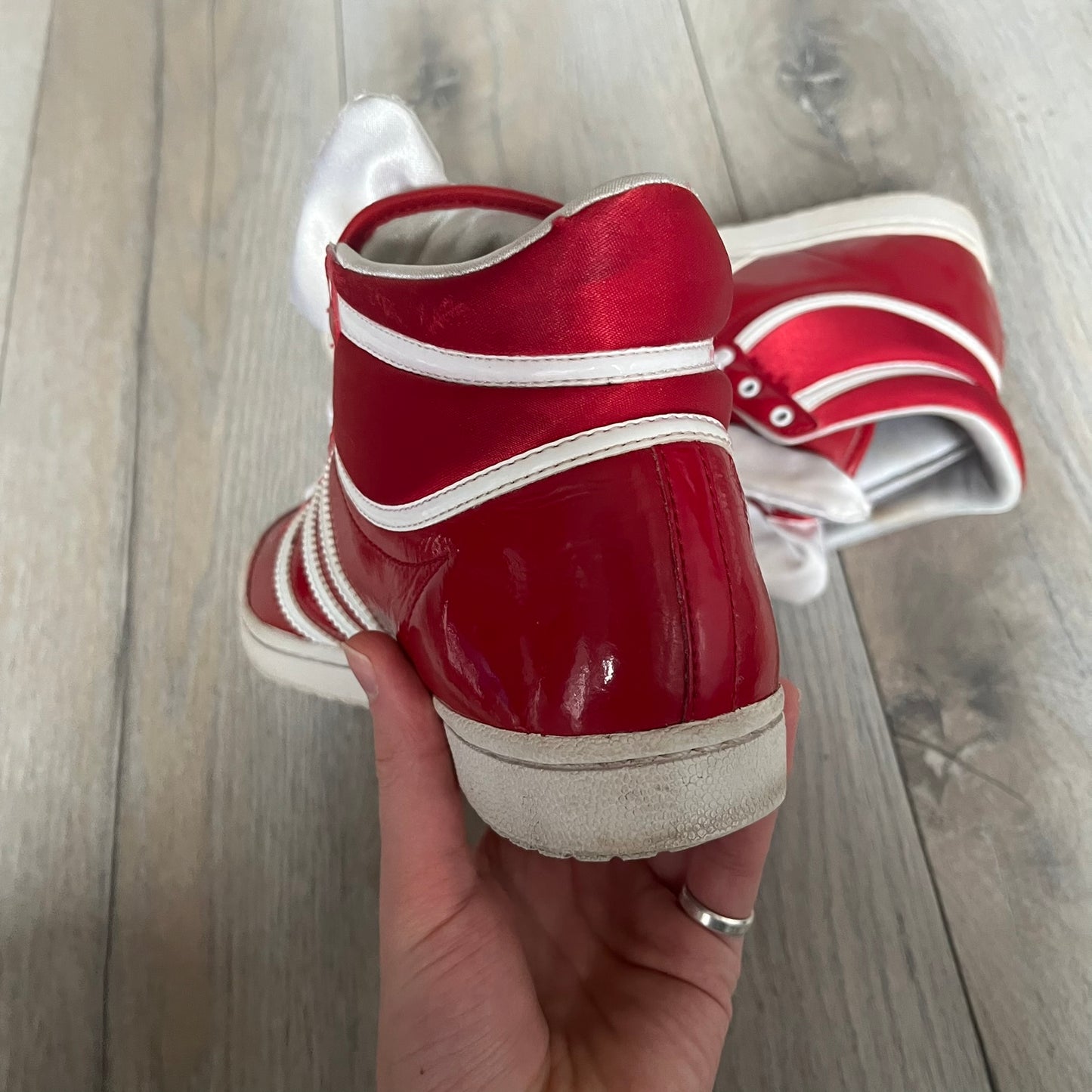 Adidas Originals Top Ten Hi Sleek Bow Sneakers are women’s high-top sneakers in University-Red and white leather. They feature a removable white bow on the tongue, white Adidas stripes, laces, and a white sole. Released under product number G61361, the sneakers include patent leather details for a polished finish.