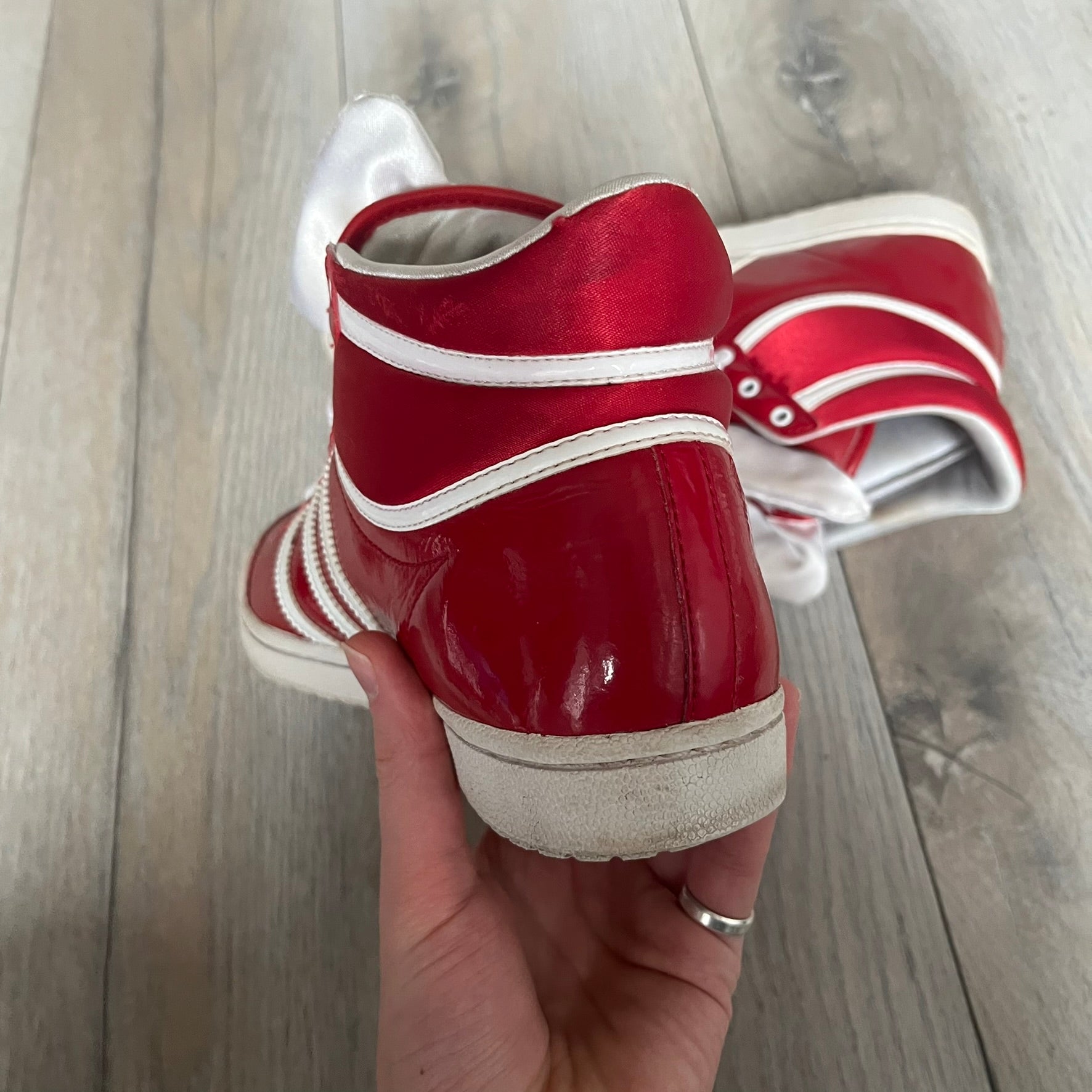 Adidas Originals Top Ten Hi Sleek Bow Sneakers are women’s high-top sneakers in University-Red and white leather. They feature a removable white bow on the tongue, white Adidas stripes, laces, and a white sole. Released under product number G61361, the sneakers include patent leather details for a polished finish.