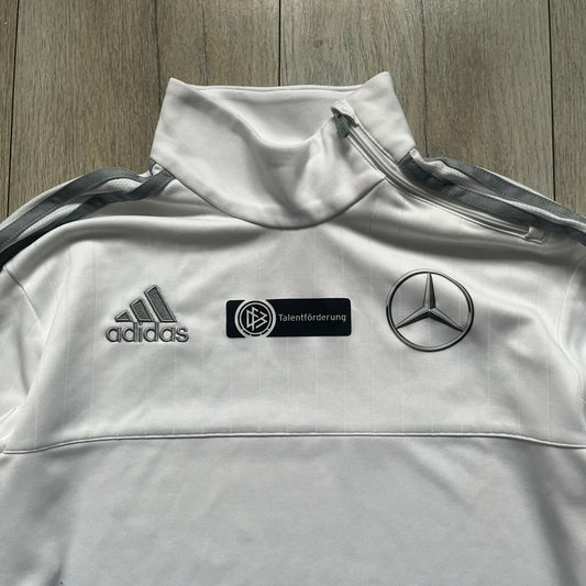 Adidas Talentförderprogramm Mercedes White Tracksuit is a white tracksuit featuring gray Adidas three-stripes running along the sleeves. The jacket displays Adidas, Mercedes, and Talentförderprogramm logos on the chest, with a white collar and a diagonal side zipper. Made with Climacool technology, it offers breathable performance for athletic wear.