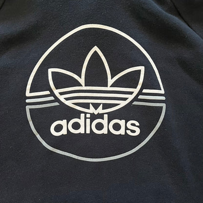 Adidas Trefoil Zip Pouch Hoodie in black, crafted from soft cotton for durability and comfort. Features a large Trefoil logo on the back within a circle, a smaller embroidered logo on the left chest, and a front zip pouch pocket. Designed with thick drawstrings and reinforced stitching, offering a sturdy, well-constructed fit.
