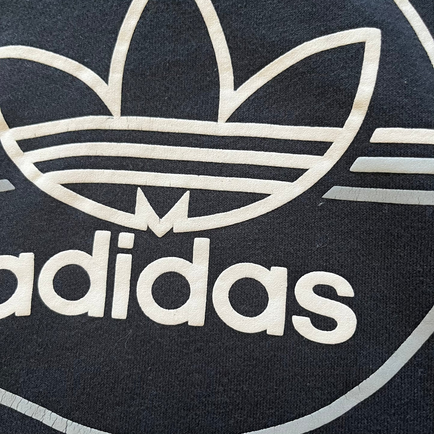 Adidas Trefoil Zip Pouch Hoodie in black, crafted from soft cotton for durability and comfort. Features a large Trefoil logo on the back within a circle, a smaller embroidered logo on the left chest, and a front zip pouch pocket. Designed with thick drawstrings and reinforced stitching, offering a sturdy, well-constructed fit.
