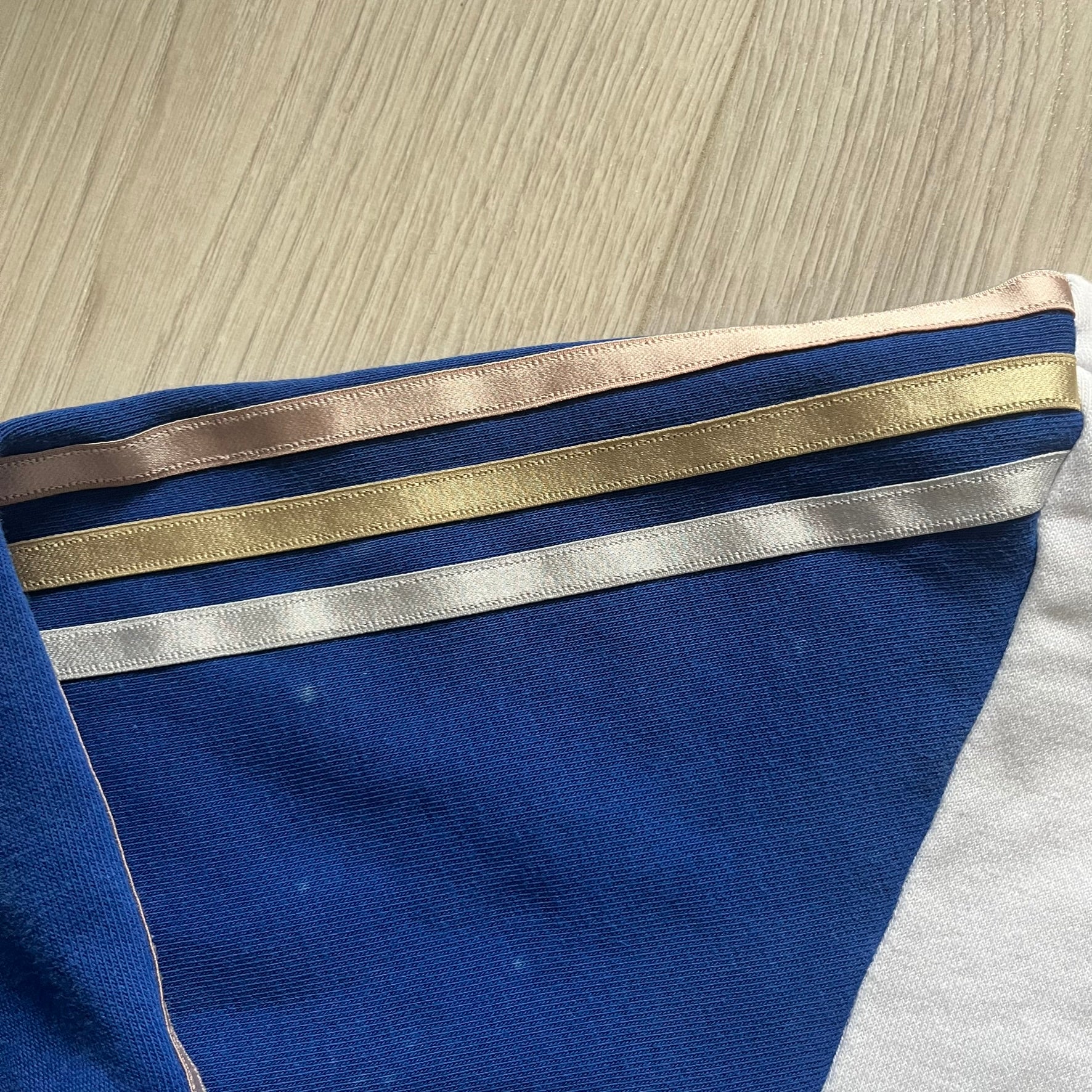 Adidas USA Olympic London 2012 Track Jacket in white with a blue sleeve featuring bronze, silver, and gold adidas stripes. Designed with a red zipper, blue collar, and embroidered adidas USA logo in a flag graphic on the chest, paired with a gold embroidered London 2012 logo on the other side. A rare piece of official Team USA gear from the London Olympic Games.