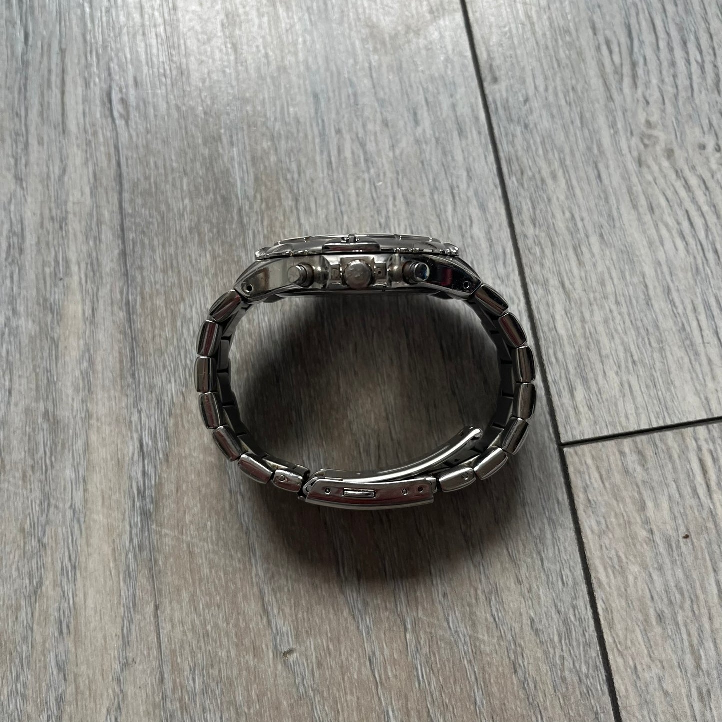 Adidas VS Chronograph 10-5010 Analog Watch is a silver-tone metal timepiece featuring a metallic blue dial with day and seconds indicators. The watch includes three sub-dials, a detailed seconds track, and three side buttons for chronograph functions. Designed with a sturdy, thick case, it comes with an extra link for adjustable sizing.