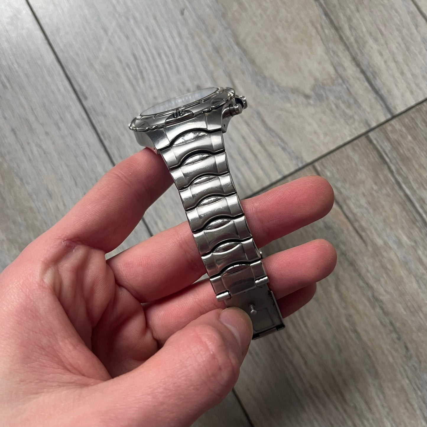 Adidas VS Chronograph 10-5010 Analog Watch is a silver-tone metal timepiece featuring a metallic blue dial with day and seconds indicators. The watch includes three sub-dials, a detailed seconds track, and three side buttons for chronograph functions. Designed with a sturdy, thick case, it comes with an extra link for adjustable sizing.