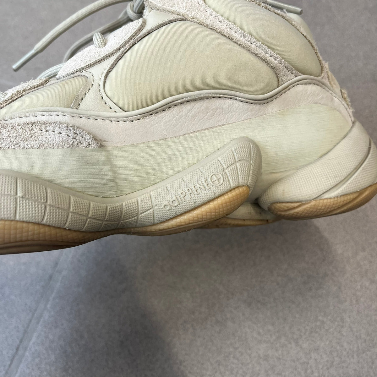 Adidas Yeezy 500 “Stone” Sneakers feature a Stone/Stone/Stone colorway with suede and neoprene paneling, reflective piping, and a pull-tab at the tongue. The sneakers have a lace-up fastening, adiPRENE midsole, and gum rubber outsole. Style FW4839, released November 23, 2019.
