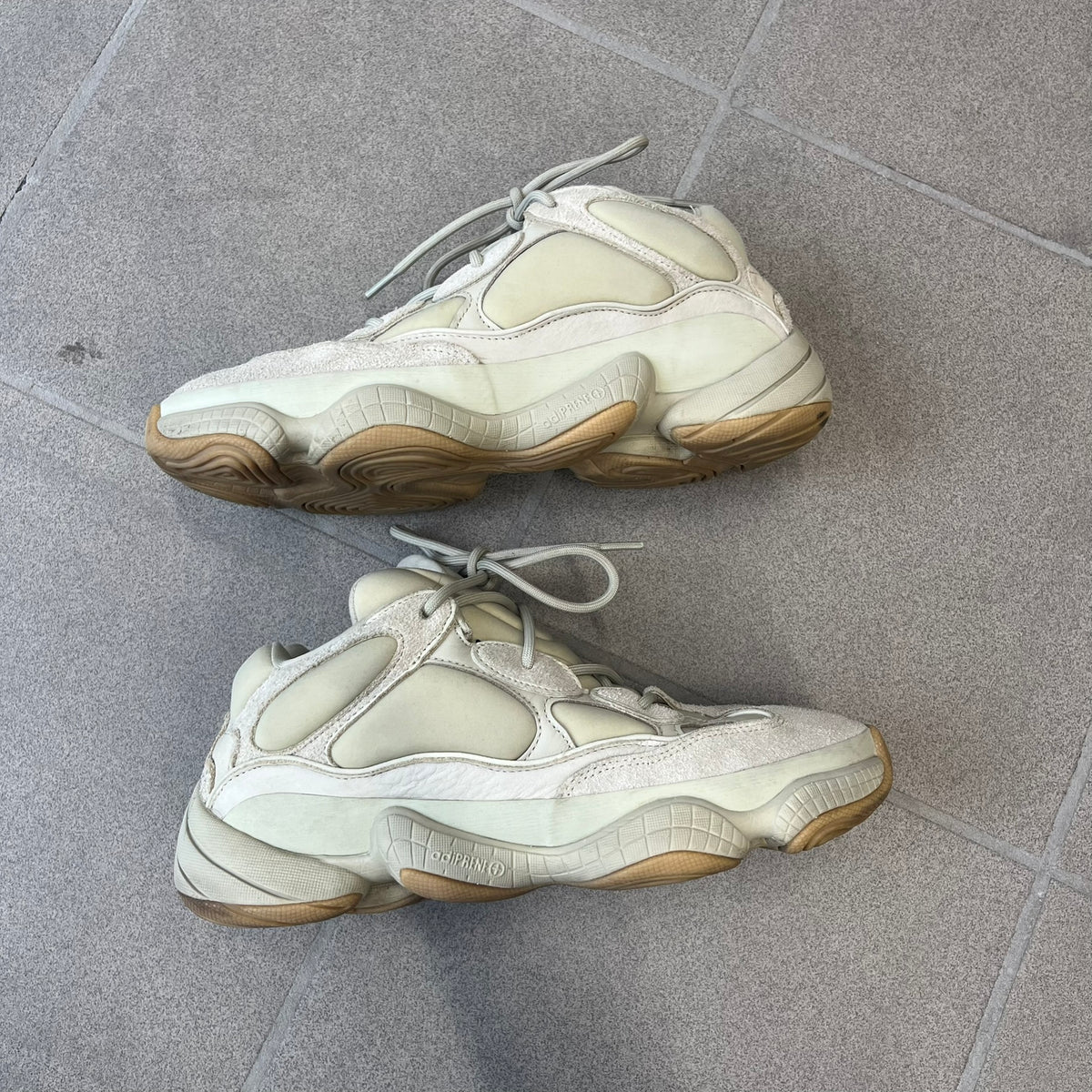 Adidas Yeezy 500 “Stone” Sneakers feature a Stone/Stone/Stone colorway with suede and neoprene paneling, reflective piping, and a pull-tab at the tongue. The sneakers have a lace-up fastening, adiPRENE midsole, and gum rubber outsole. Style FW4839, released November 23, 2019.
