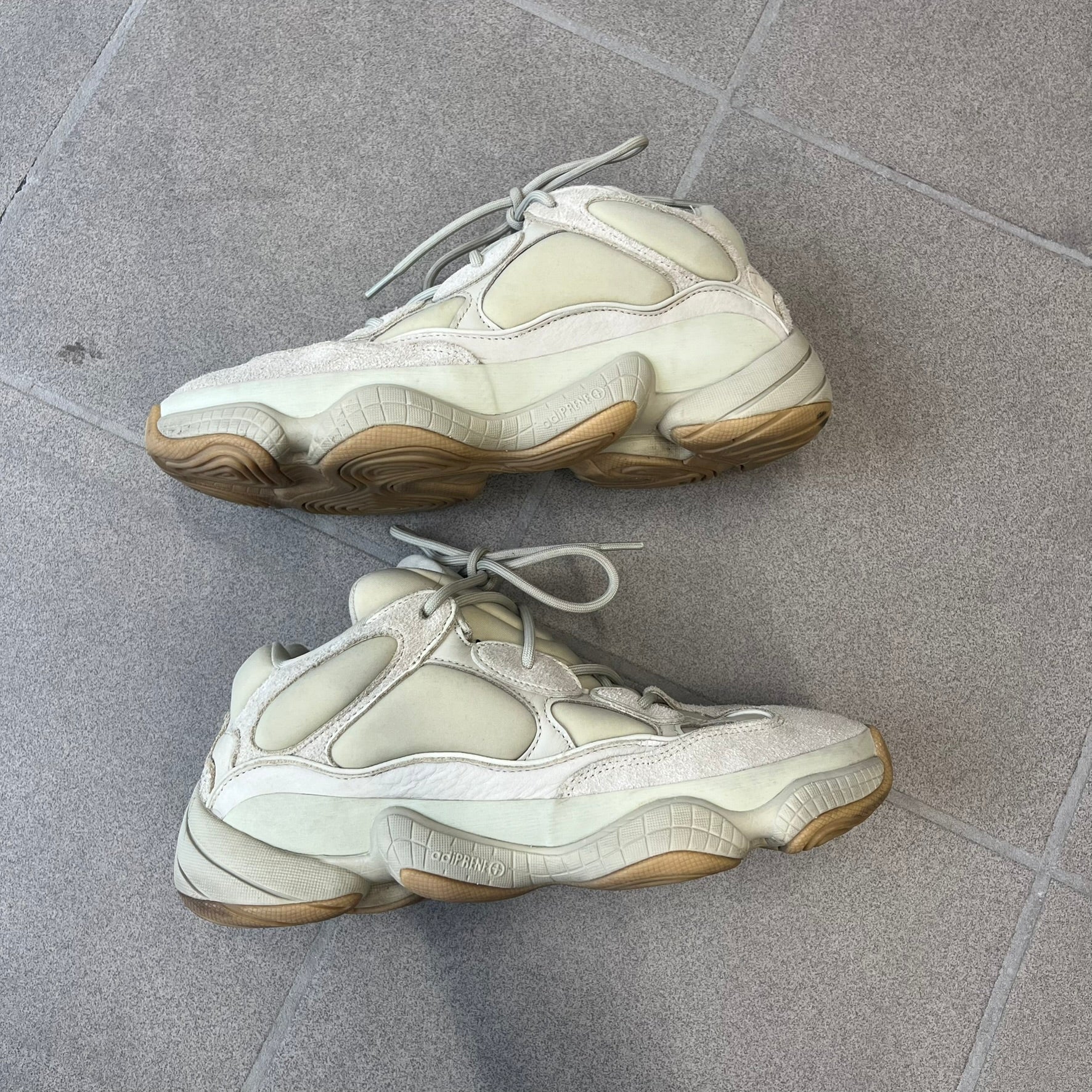 Adidas Yeezy 500 “Stone” Sneakers feature a Stone/Stone/Stone colorway with suede and neoprene paneling, reflective piping, and a pull-tab at the tongue. The sneakers have a lace-up fastening, adiPRENE midsole, and gum rubber outsole. Style FW4839, released November 23, 2019.
