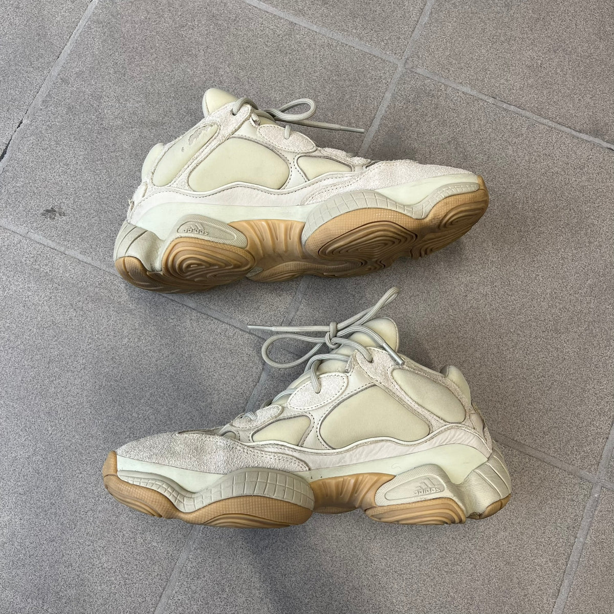 Adidas Yeezy 500 “Stone” Sneakers feature a Stone/Stone/Stone colorway with suede and neoprene paneling, reflective piping, and a pull-tab at the tongue. The sneakers have a lace-up fastening, adiPRENE midsole, and gum rubber outsole. Style FW4839, released November 23, 2019.
