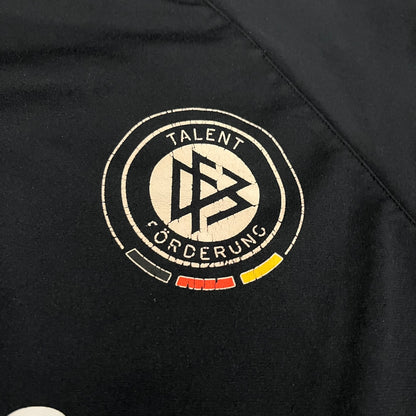 Adidas 2004/05 Germany Longsleeve in black featuring the Talent Förderung logo on the front and a center Adidas chest logo. Designed with classic three white stripes along the wrists and multiple sponsor logos on the back, including Mercedes, Adidas, and Nintendo. Made with Climawear fabric for comfort and performance.