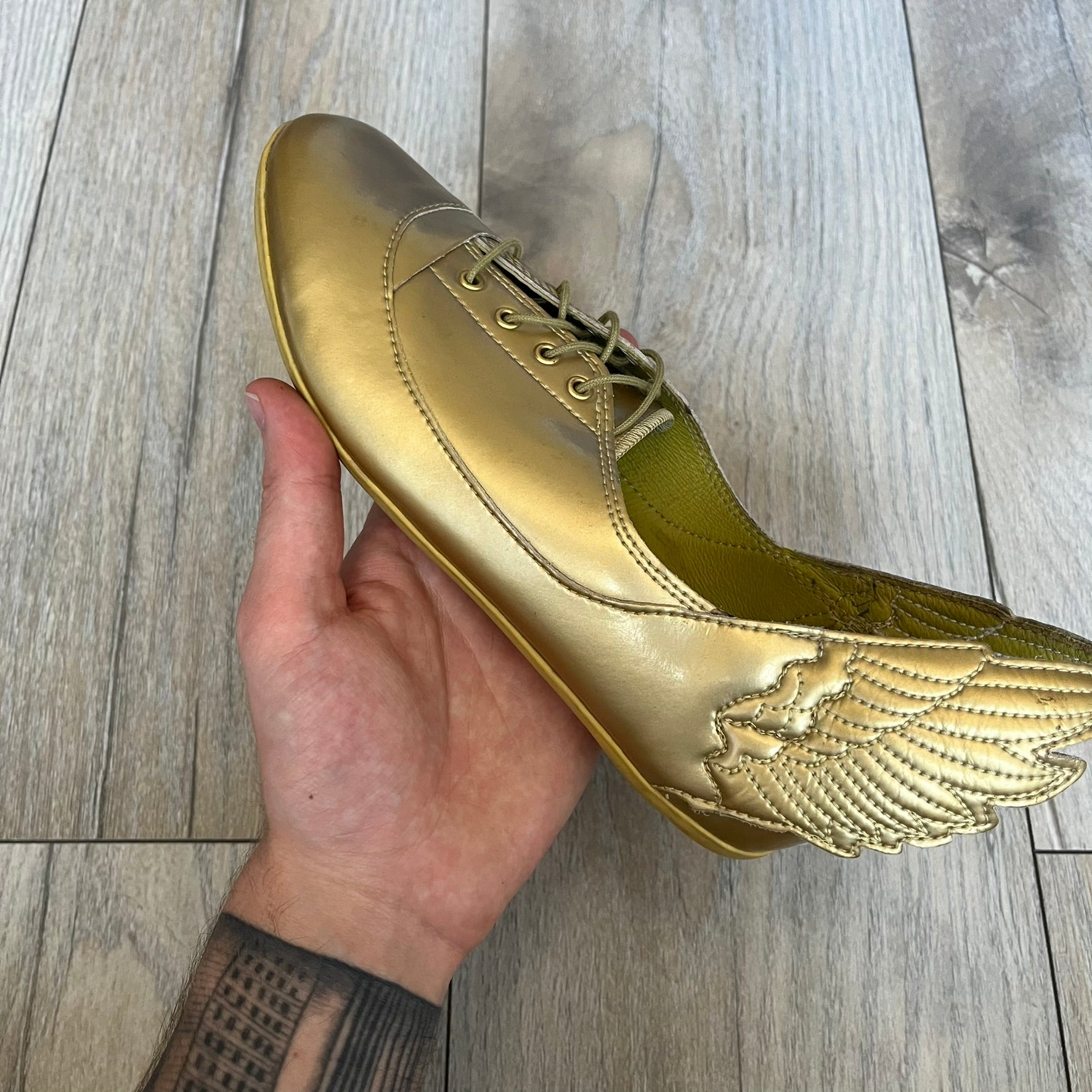 Adidas x Jeremy Scott 2011 Wings Gold Ballet Flats are a rare footwear design combining a classic ballet flat silhouette with Jeremy Scott’s signature wing motif. The shoes feature a fully metallic gold finish with visible stitching throughout the upper and wing construction. Small 3D wings extend from both sides of the heel area, creating the iconic Wings look in a streamlined form. Finished with a Trefoil Adidas logo on the back.