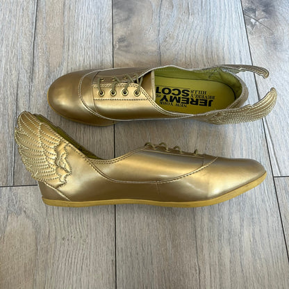 Adidas x Jeremy Scott 2011 Wings Gold Ballet Flats are a rare footwear design combining a classic ballet flat silhouette with Jeremy Scott’s signature wing motif. The shoes feature a fully metallic gold finish with visible stitching throughout the upper and wing construction. Small 3D wings extend from both sides of the heel area, creating the iconic Wings look in a streamlined form. Finished with a Trefoil Adidas logo on the back.