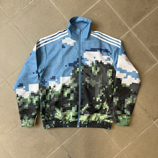 Adidas x Minecraft Movie SS25 Track Top (Style: JZ9921) is a Spring/Summer 2025 collaboration featuring an all-over Minecraft landscape print with a pixelated sky across the upper half and grass terrain across the lower half. The track jacket has white Three Stripes along the shoulders and sleeves, a full-zip front with a pixelated Trefoil logo zipper pull, and ribbed cuffs and hem. Finished in Hazy Blue, Magic Lime, and Tribe Green.