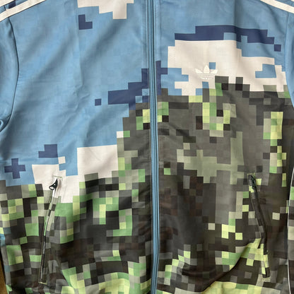 Adidas x Minecraft Movie SS25 Track Top (Style: JZ9921) is a Spring/Summer 2025 collaboration featuring an all-over Minecraft landscape print with a pixelated sky across the upper half and grass terrain across the lower half. The track jacket has white Three Stripes along the shoulders and sleeves, a full-zip front with a pixelated Trefoil logo zipper pull, and ribbed cuffs and hem. Finished in Hazy Blue, Magic Lime, and Tribe Green.