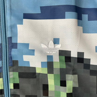 Adidas x Minecraft Movie SS25 Track Top (Style: JZ9921) is a Spring/Summer 2025 collaboration featuring an all-over Minecraft landscape print with a pixelated sky across the upper half and grass terrain across the lower half. The track jacket has white Three Stripes along the shoulders and sleeves, a full-zip front with a pixelated Trefoil logo zipper pull, and ribbed cuffs and hem. Finished in Hazy Blue, Magic Lime, and Tribe Green.