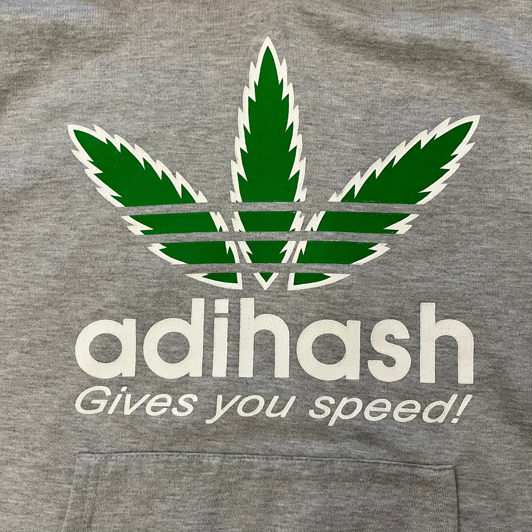 This Adihash “Gives You Speed!” Hoodie features a playful twist on the classic adidas emblem, replacing the trefoil with three marijuana leaves and big Adihash branding. Made from a soft polyester–cotton blend, it offers everyday comfort with a standard pouch pocket and a clean grey finish. Produced on a Lemon Collection blank.