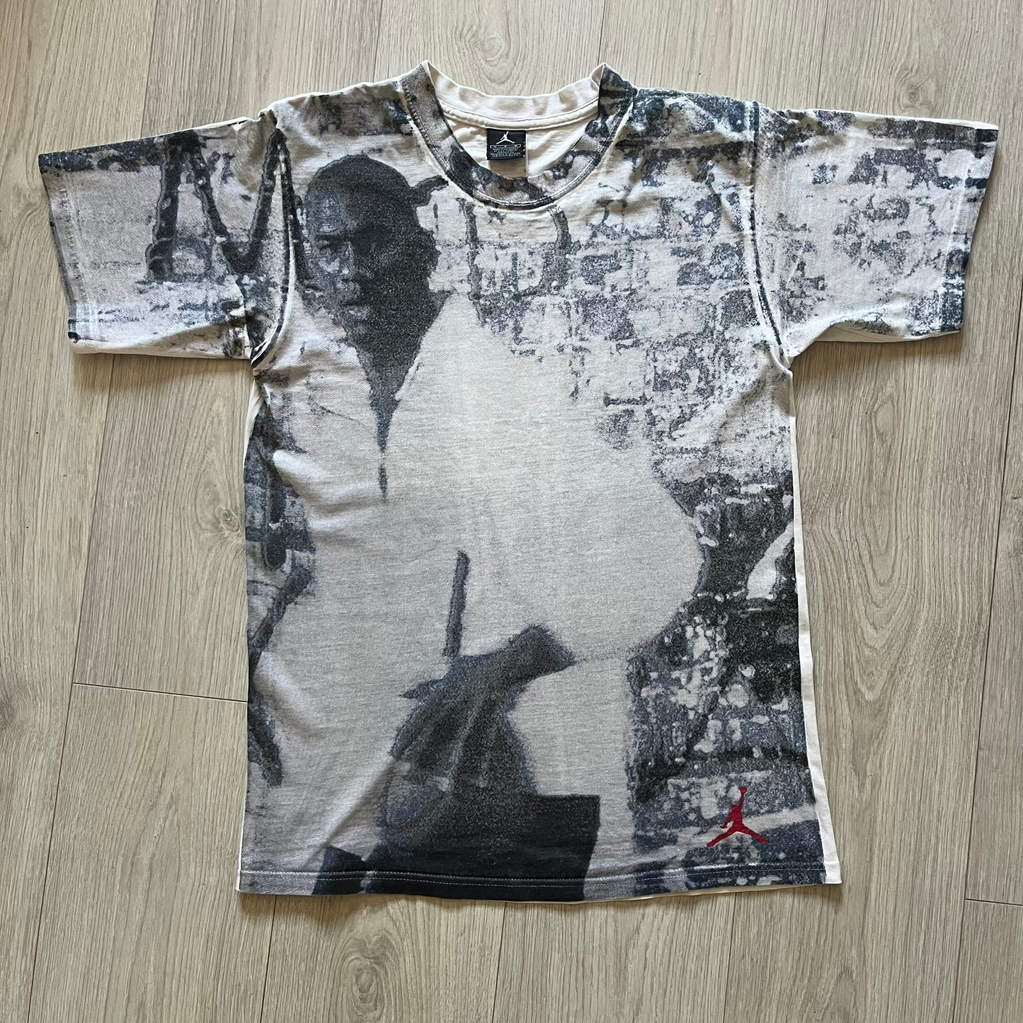Air Jordan 2000’s All Over Print Tee featuring a bold full print of Michael Jordan in black, white, and blue across the front. A small red Jumpman logo sits at the bottom, while the back showcases a large Air Jordan logo with embroidered small red logo just under the collar. A rare vintage piece from the 2000s that captures peak Jordan era style.