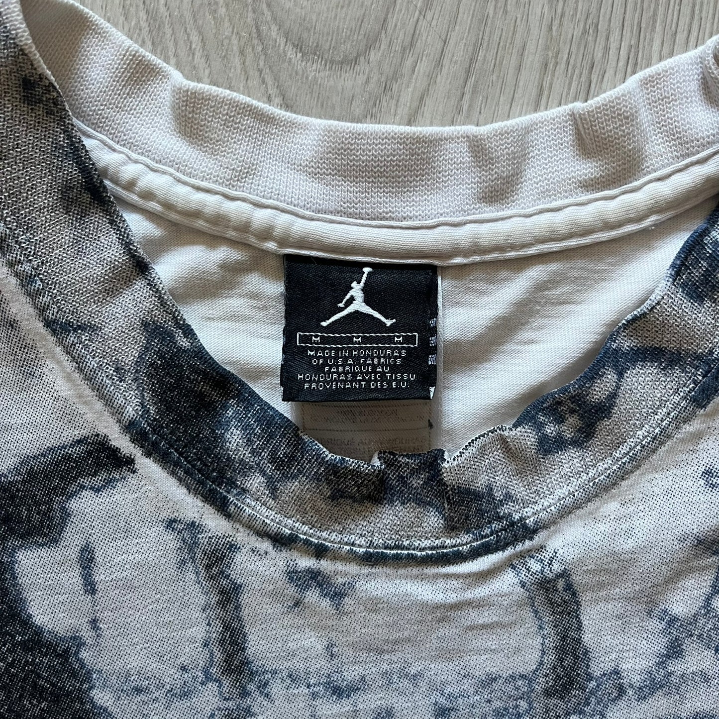 Air Jordan 2000’s All Over Print Tee featuring a bold full print of Michael Jordan in black, white, and blue across the front. A small red Jumpman logo sits at the bottom, while the back showcases a large Air Jordan logo with embroidered small red logo just under the collar. A rare vintage piece from the 2000s that captures peak Jordan era style.