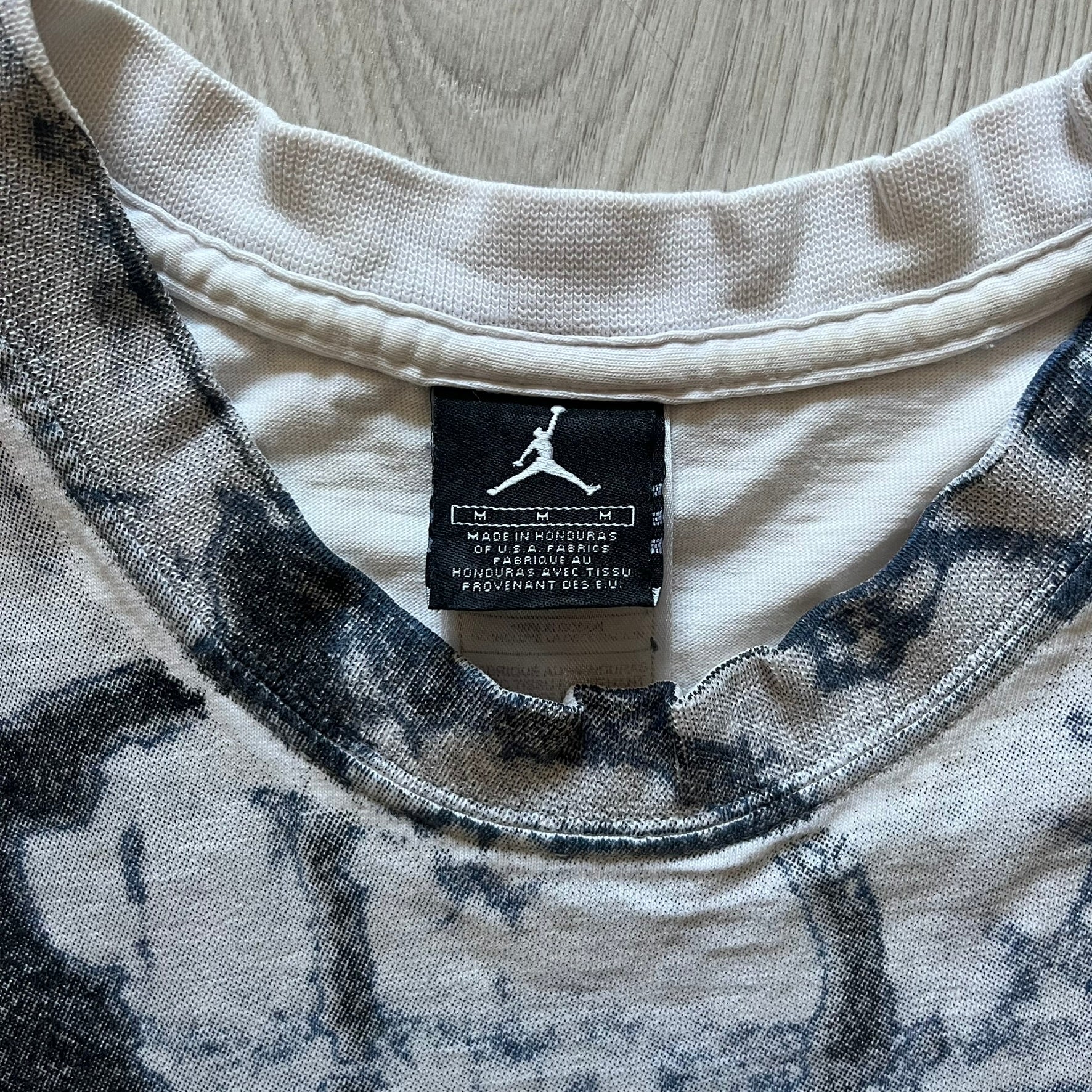 Air Jordan 2000’s All Over Print Tee featuring a bold full print of Michael Jordan in black, white, and blue across the front. A small red Jumpman logo sits at the bottom, while the back showcases a large Air Jordan logo with embroidered small red logo just under the collar. A rare vintage piece from the 2000s that captures peak Jordan era style.