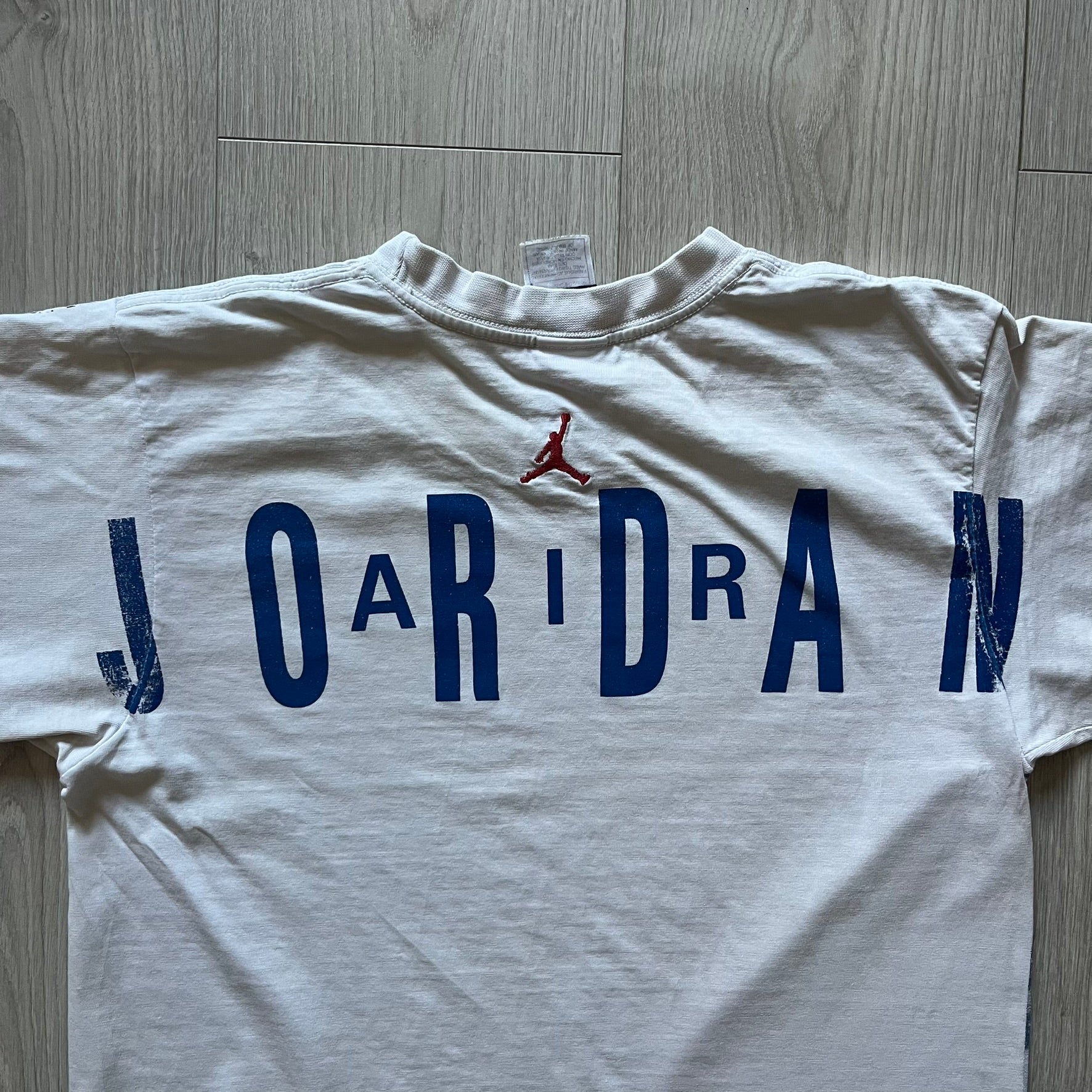 Air Jordan 2000’s All Over Print Tee featuring a bold full print of Michael Jordan in black, white, and blue across the front. A small red Jumpman logo sits at the bottom, while the back showcases a large Air Jordan logo with embroidered small red logo just under the collar. A rare vintage piece from the 2000s that captures peak Jordan era style.