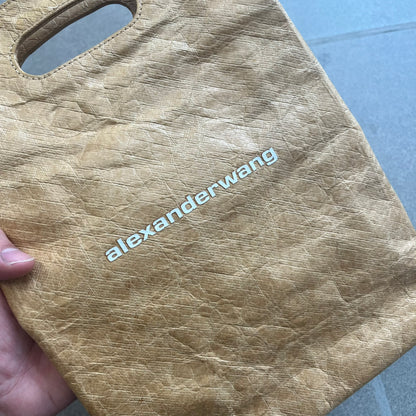 Alexander Wang x McDonald’s 2019 Golden Lunch Bag is a limited edition collaboration accessory made from thick waterproof DuPont Tyvek paper with a leather-like texture. Designed to resemble a classic McDonald’s takeaway bag, it features a small white Alexander Wang logo on the front and a subtle McDonald’s Golden Arches logo on the side. The piece combines fast-food nostalgia with Alexander Wang’s minimalist luxury approach.
