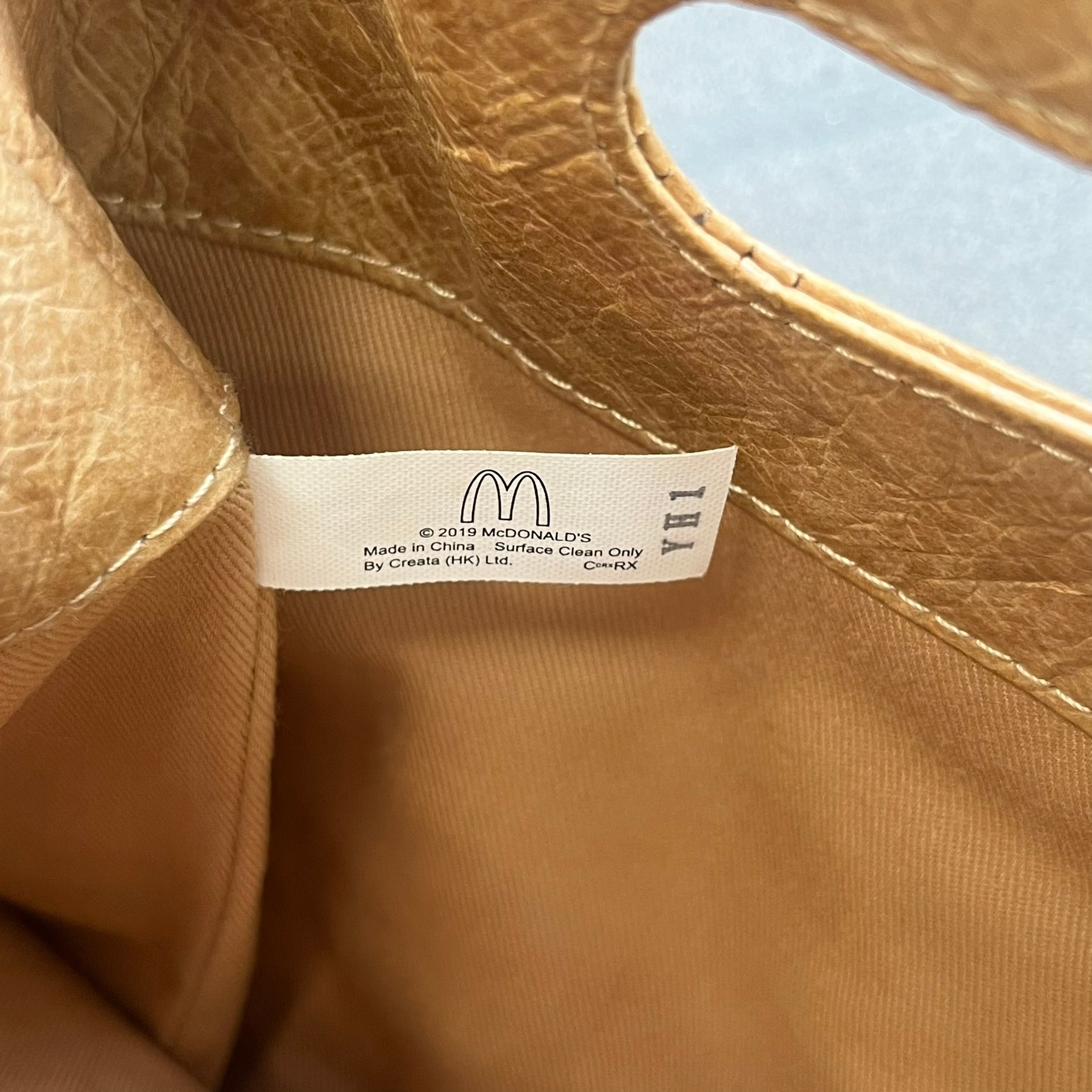 Alexander Wang x McDonald’s 2019 Golden Lunch Bag is a limited edition collaboration accessory made from thick waterproof DuPont Tyvek paper with a leather-like texture. Designed to resemble a classic McDonald’s takeaway bag, it features a small white Alexander Wang logo on the front and a subtle McDonald’s Golden Arches logo on the side. The piece combines fast-food nostalgia with Alexander Wang’s minimalist luxury approach.
