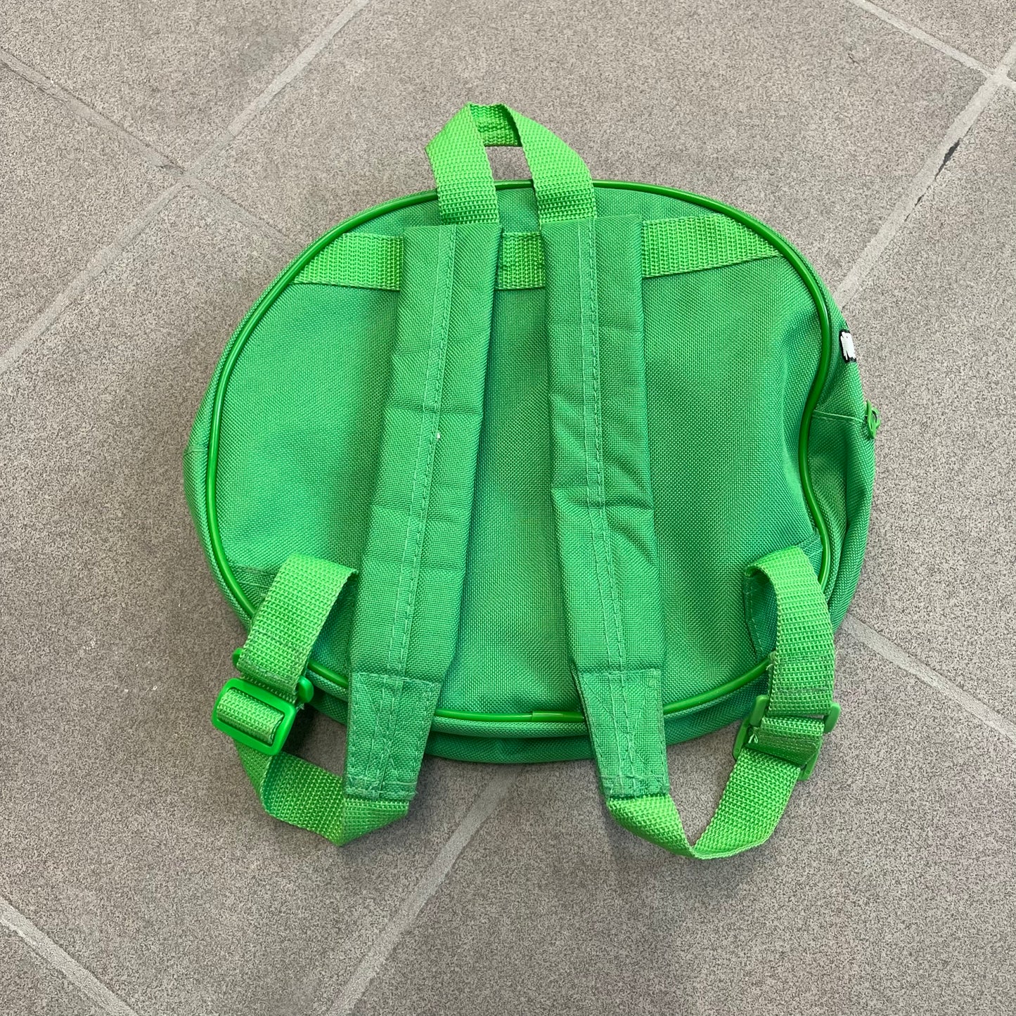 Angry Birds 2010s Bad Piggies Green Backpack is a small circular backpack shaped like the head of a Bad Piggies character. The front features the pig’s scared facial expression, while the side has an Angry Birds logo. The interior includes an all-over pig head monogram lining and an official Angry Birds licensed tag. The backpack is finished with really short adjustable shoulder straps.