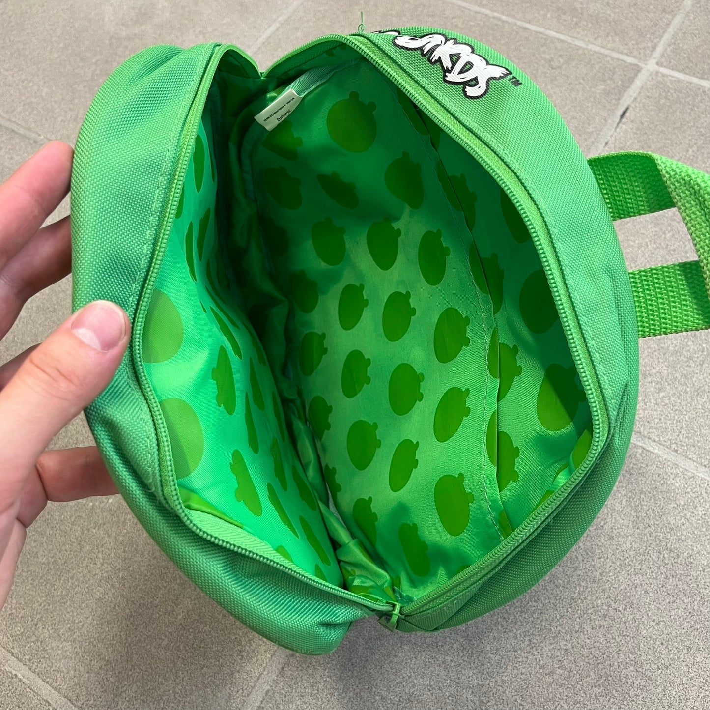 Angry Birds 2010s Bad Piggies Green Backpack is a small circular backpack shaped like the head of a Bad Piggies character. The front features the pig’s scared facial expression, while the side has an Angry Birds logo. The interior includes an all-over pig head monogram lining and an official Angry Birds licensed tag. The backpack is finished with really short adjustable shoulder straps.