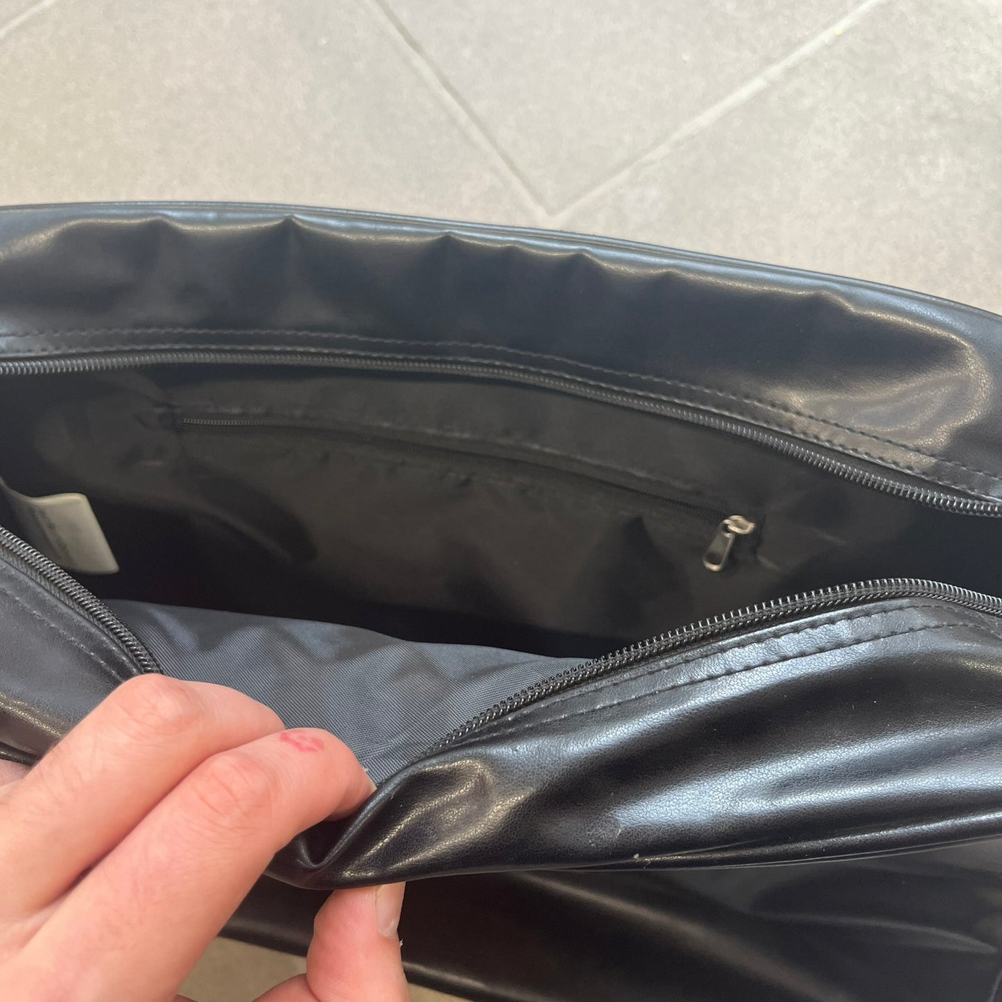Angry Birds 2010s Black Bomb Bird Shoulder Bag is a black messenger-style bag made from a leather-like material. It features one main compartment with a smaller internal pocket. The front is designed with a large graphic of Bomb, the black Angry Birds character. The interior includes official Angry Birds 2009-2013 licensing.
