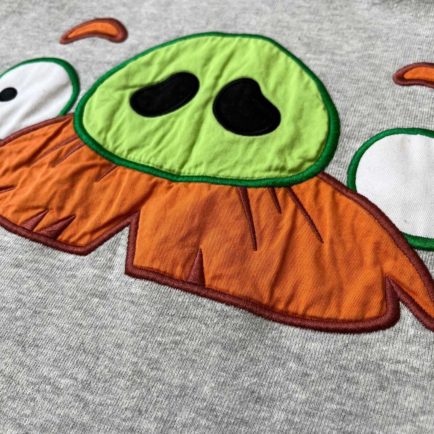 Angry Birds Three Star 2012 Foreman Pig Gray Hoodie features a grey hoodie design with a 3D-style front graphic of Foreman Pig, showing his recognizable eyes, nose, and mustache details. The back features a grey circular "Three Star" Angry Birds graphic, while the inside of the hood is finished with an orange lining.