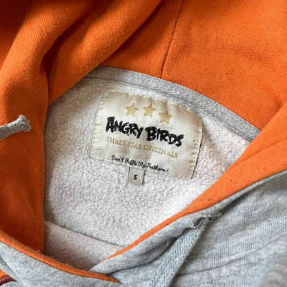 Angry Birds Three Star 2012 Foreman Pig Gray Hoodie features a grey hoodie design with a 3D-style front graphic of Foreman Pig, showing his recognizable eyes, nose, and mustache details. The back features a grey circular "Three Star" Angry Birds graphic, while the inside of the hood is finished with an orange lining.