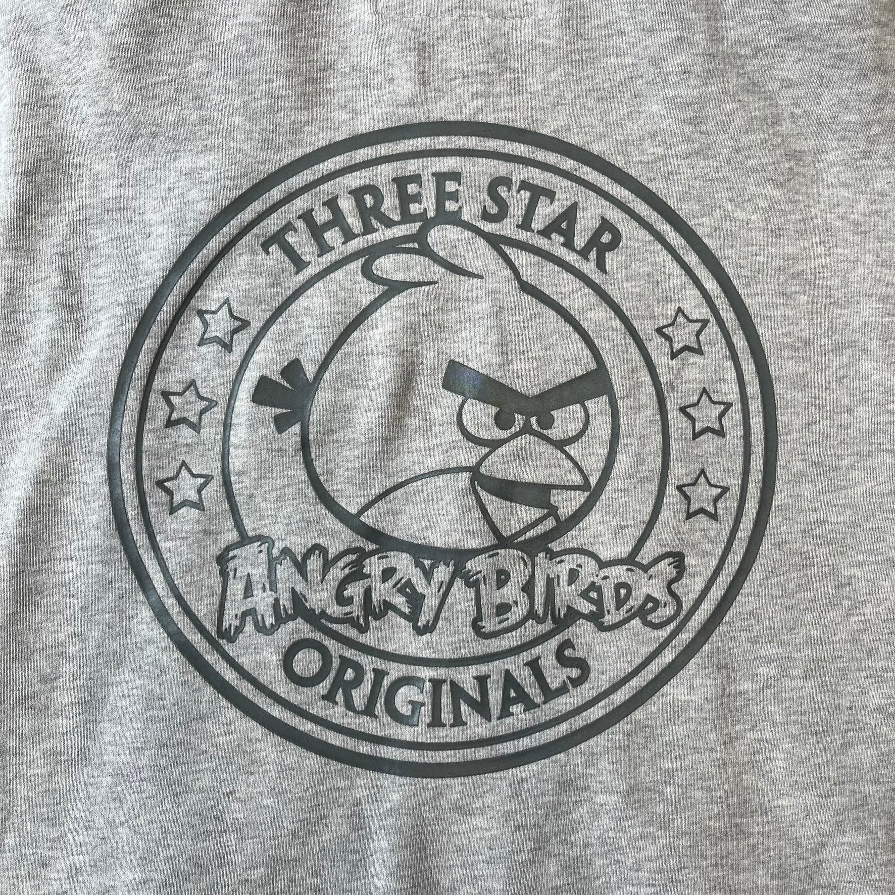 Angry Birds Three Star 2012 Foreman Pig Gray Hoodie features a grey hoodie design with a 3D-style front graphic of Foreman Pig, showing his recognizable eyes, nose, and mustache details. The back features a grey circular "Three Star" Angry Birds graphic, while the inside of the hood is finished with an orange lining.