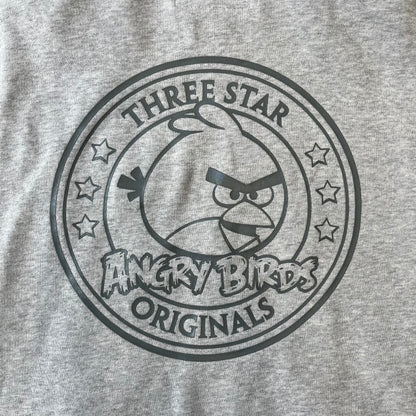 Angry Birds Three Star 2012 Foreman Pig Gray Hoodie features a grey hoodie design with a 3D-style front graphic of Foreman Pig, showing his recognizable eyes, nose, and mustache details. The back features a grey circular "Three Star" Angry Birds graphic, while the inside of the hood is finished with an orange lining.