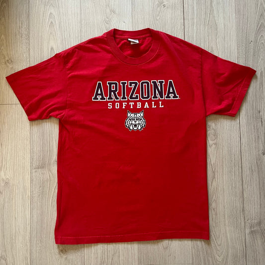 Red t-shirt with 'Arizona Softball' text and logo on a wooden surface