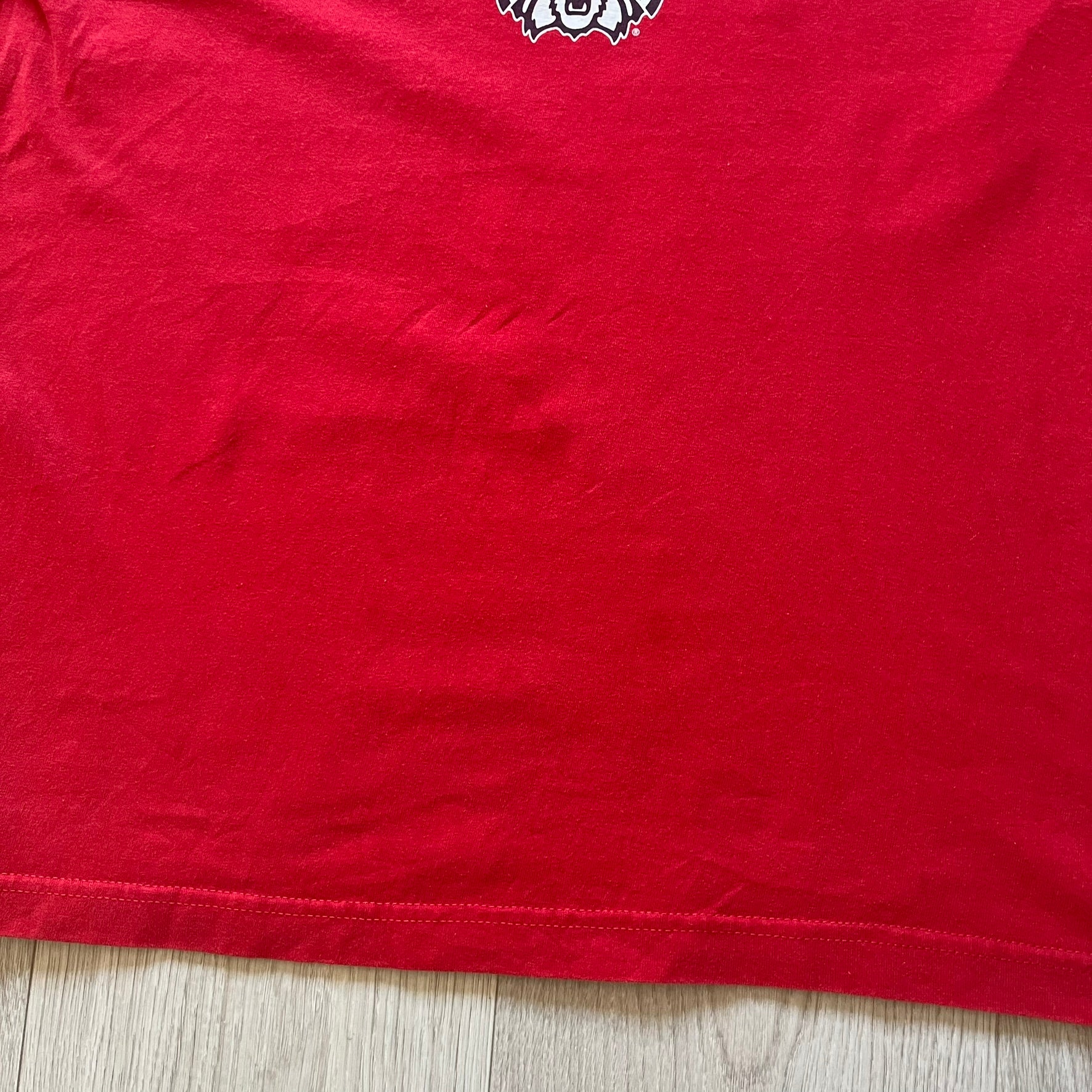 Red t-shirt with a logo on a wooden surface