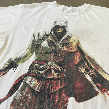 Assassin's Creed 2 Promo 2010 White Tee features a white 100% cotton construction with a large colorful graphic of Ezio Auditore da Firenze on the front. The Assassin's Creed 2 logo appears underneath the character, finished with a licensed neck tag.
