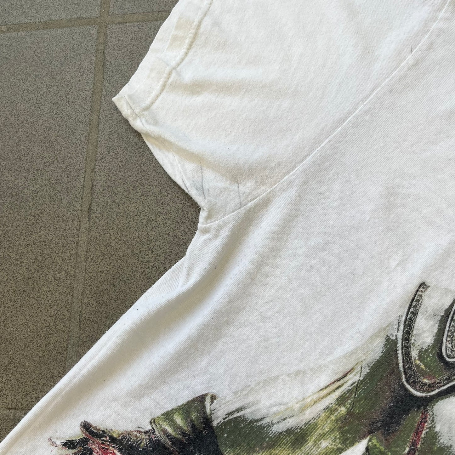 Assassin's Creed 2 Promo 2010 White Tee features a white 100% cotton construction with a large colorful graphic of Ezio Auditore da Firenze on the front. The Assassin's Creed 2 logo appears underneath the character, finished with a licensed neck tag.
