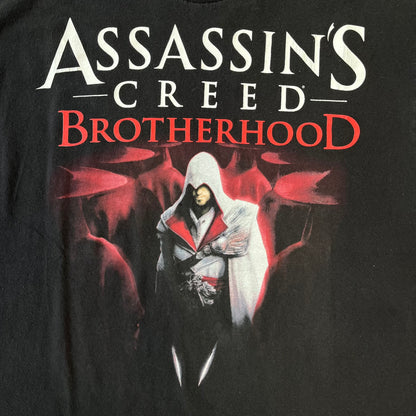 Assassin's Creed Brotherhood 2010 Black Promo Tee features a black construction with the Assassin's Creed Brotherhood cover printed on the front, showing Ezio Auditore with the large white and red text above him. Finished with a washed-off licensed neck tag