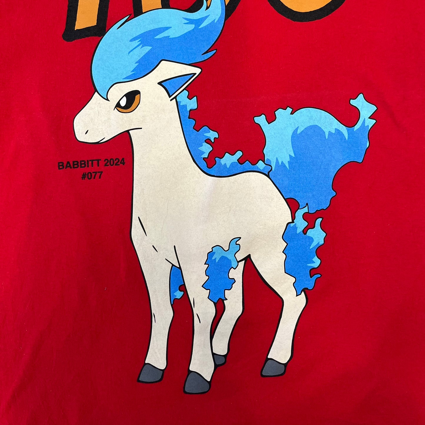 Asspizza 2024 Shiny Ponyta Red Tee is a red T-shirt featuring a shiny Ponyta graphic on the front with a yellow “730” number printed above. Next to the Ponyta graphic is a small black “Babbitt 2024 #077” text detail. The shirt is printed on a Colombia blank.
