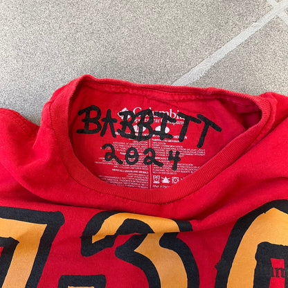 Asspizza 2024 Shiny Ponyta Red Tee is a red T-shirt featuring a shiny Ponyta graphic on the front with a yellow “730” number printed above. Next to the Ponyta graphic is a small black “Babbitt 2024 #077” text detail. The shirt is printed on a Colombia blank.
