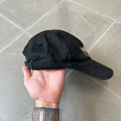 Balenciaga 2017 Political Campaign Baseball Cap features a washed black/smoked grey cotton drill construction with a curved brim. The front has an embroidered white Balenciaga logo above red and white curved stripes, with “2017” embroidered in white underneath. Made from 100% cotton.
