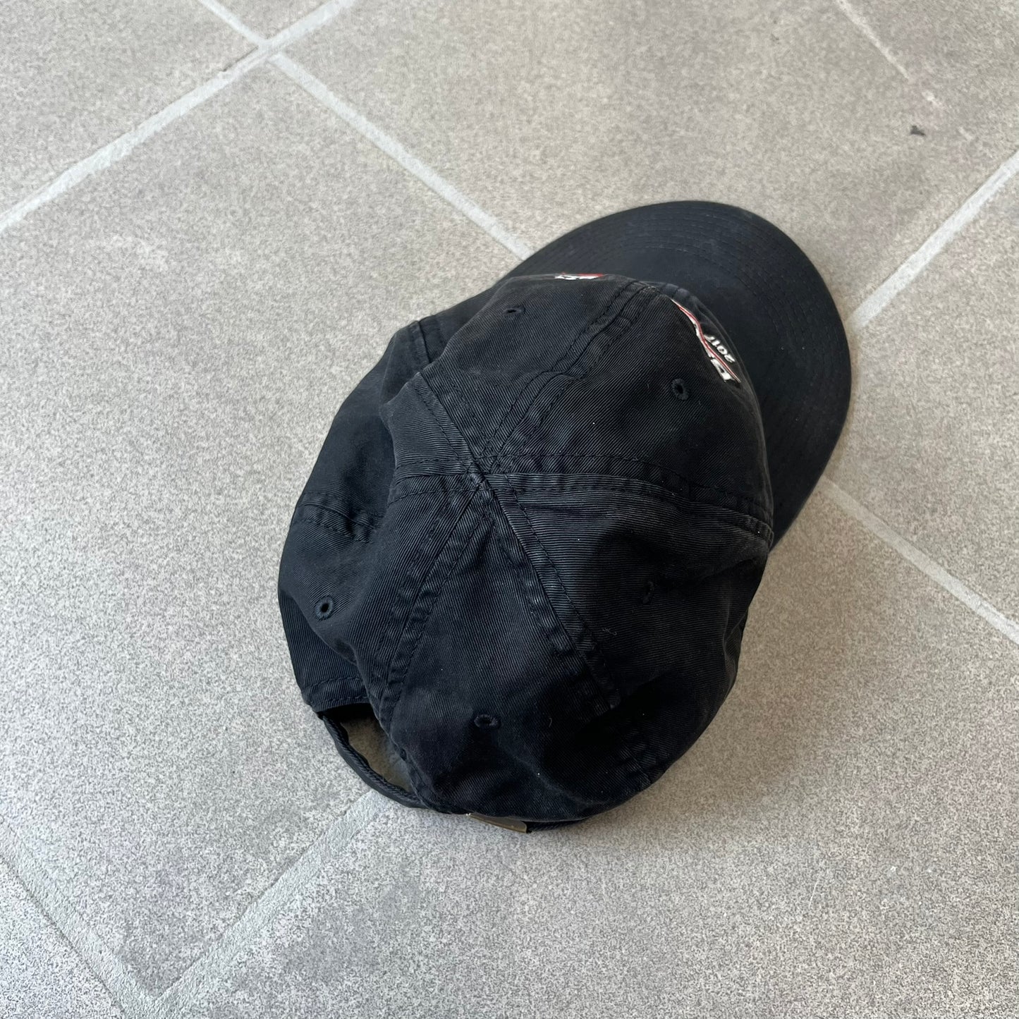 Balenciaga 2017 Political Campaign Baseball Cap features a washed black/smoked grey cotton drill construction with a curved brim. The front has an embroidered white Balenciaga logo above red and white curved stripes, with “2017” embroidered in white underneath. Made from 100% cotton.
