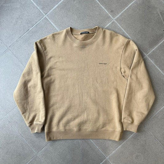 Balenciaga 2019 Khaki Small Logo Crewneck features a khaki 100% cotton construction with thick ribbed hems. A small black Balenciaga copyright logo is printed on the left chest. Made in Portugal.