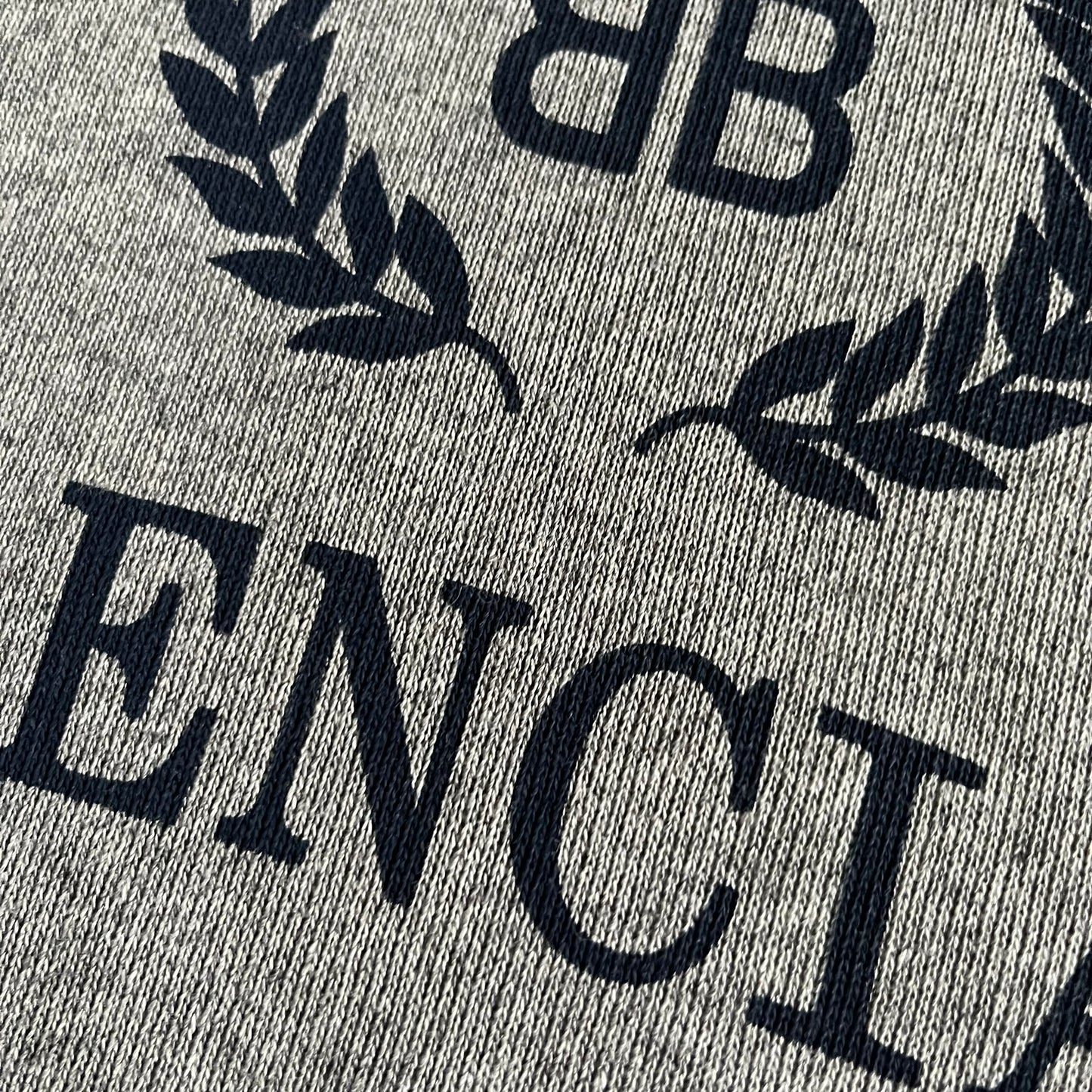 Balenciaga BB Crest Logo Hoodie in Heather Grey, crafted in Portugal from a heavyweight cotton-blend fleece (76% cotton, 24% polyester). The heather grey base features a dark navy BB emblem framed by laurel leaves and the Balenciaga logo text. Finished with dropped shoulders, ribbed edges, and a spacious front pocket, this oversized hoodie exemplifies elevated comfort and craftsmanship.