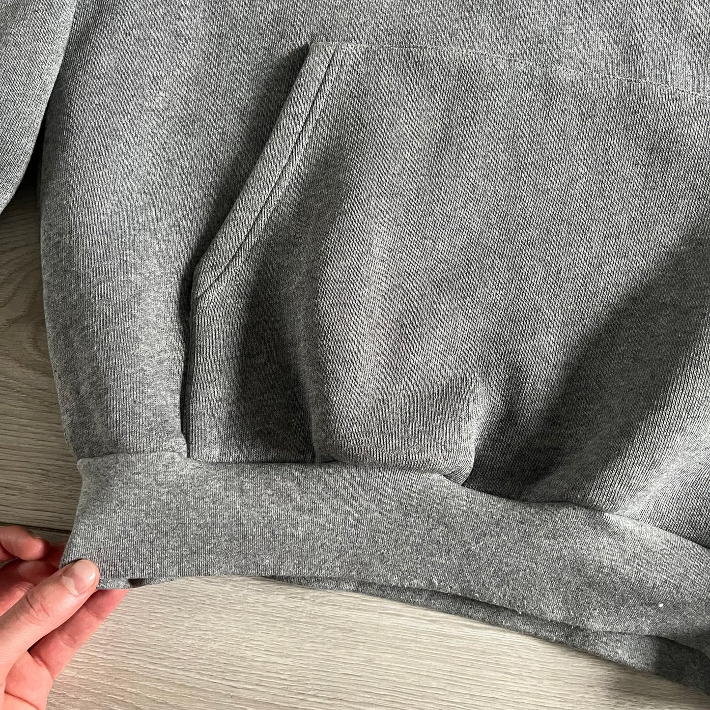 Balenciaga BB Crest Logo Hoodie in Heather Grey, crafted in Portugal from a heavyweight cotton-blend fleece (76% cotton, 24% polyester). The heather grey base features a dark navy BB emblem framed by laurel leaves and the Balenciaga logo text. Finished with dropped shoulders, ribbed edges, and a spacious front pocket, this oversized hoodie exemplifies elevated comfort and craftsmanship.